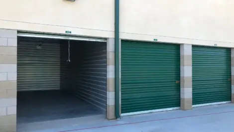Three green doored storage units with one open.